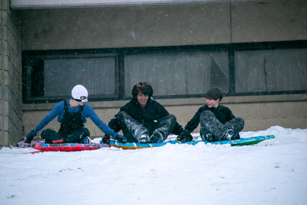 Three local teens hold sleds as they take another ride down the hill