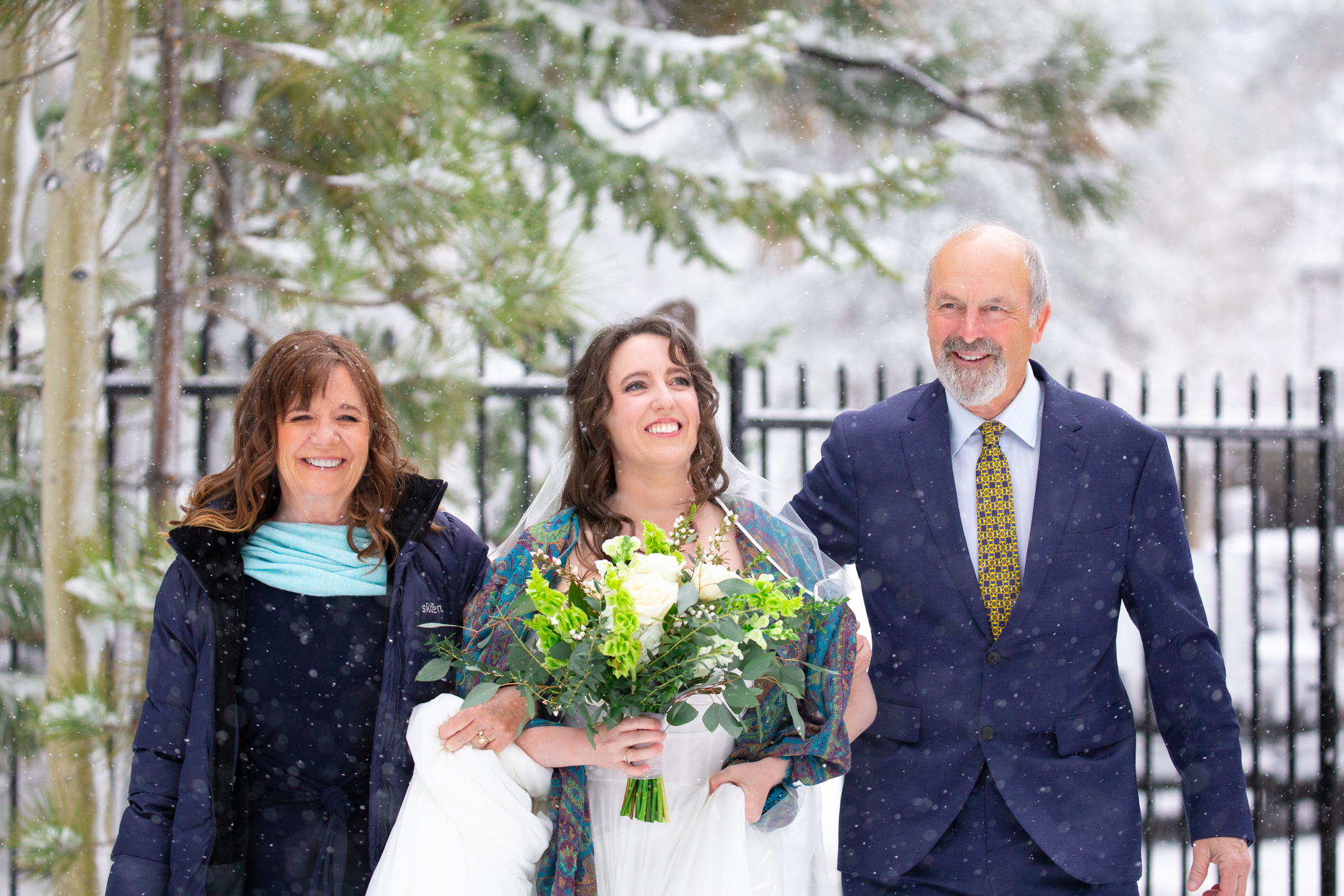 A May Bride in Lake Tahoe taking in the surprise snow storm with her parents arm in arm 