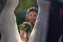 Flower girl peeps between two wedding dresses in Sparks, NV